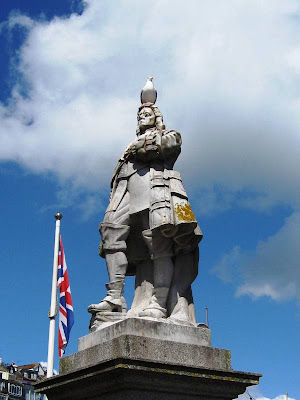 Stern stone statue of a man with a gull on his head