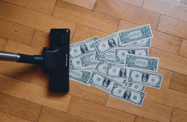 dollar bills being vacuumed on a wooden floor