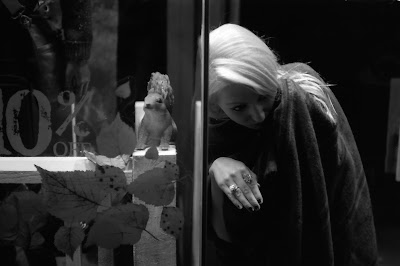 Girl with a plastic squirrel in a shop front