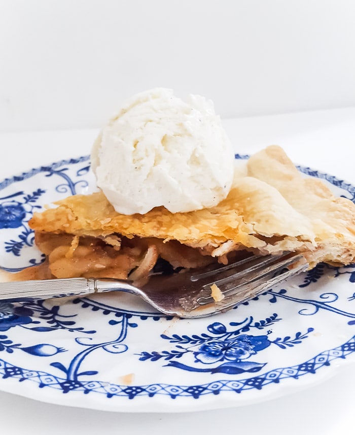apple pie slice with vanilla ice cream on blue and white vintage plate