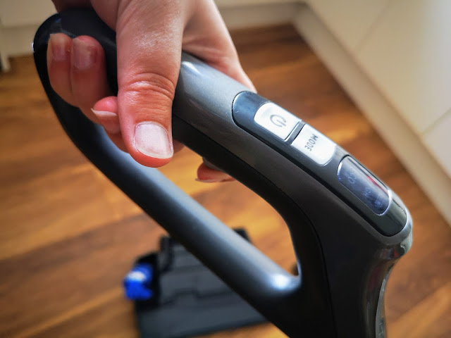 Close up image of the VAX ONEPWR Hard Floor Cleaner being used in floor washing mode. Image shows a hand on the trigger required to release the cleaning solution.