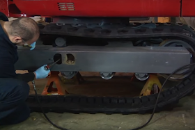 Man changes a track on a Takeuchi Excavator