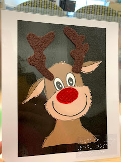 an image of a black background with a reindeer cartoon smiling with antlers and nose made tactile