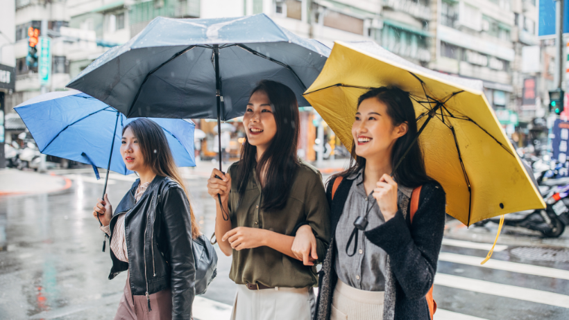 asian women walking in the rain with umbrella