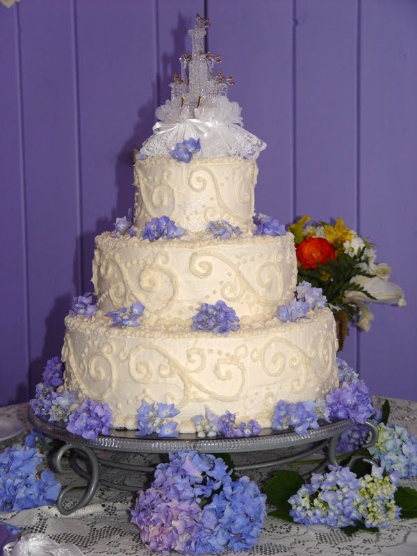 Three tier white wedding cake with swirls and fresh hydrangeas