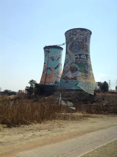 Tall power plant shaped funnels with graffiti mural painted on it of artisans and local craftsman working