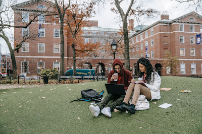 Yeşil çimlerde oturan üniversite öğrencileri