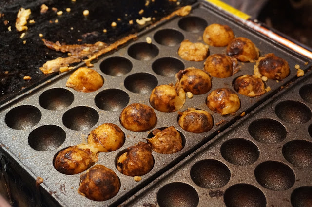 Rows of takoyaki balls on a hot plate