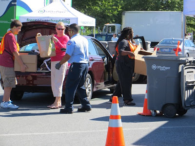 A volunteer and worker unload paper from resident's car.