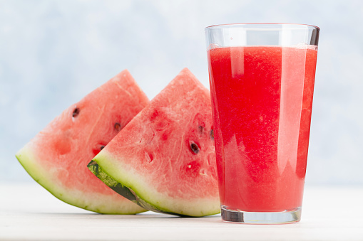 Water melon juice in a glass and freshly cut watermelon