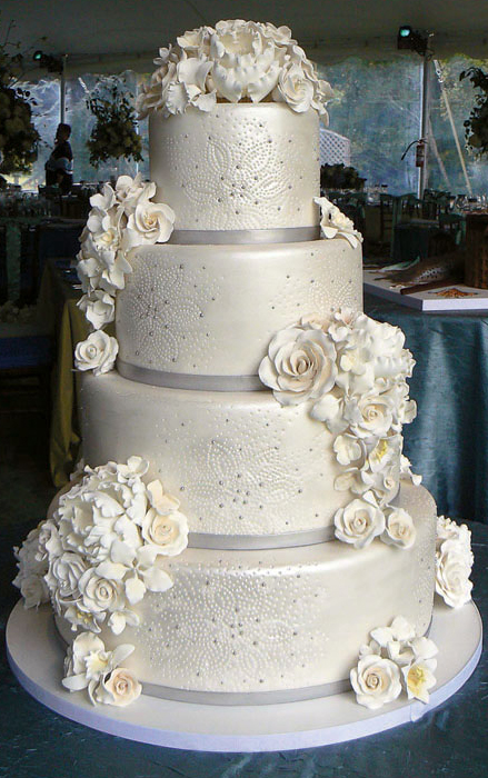 The traditional cake is white round tiered and has flowers as accents