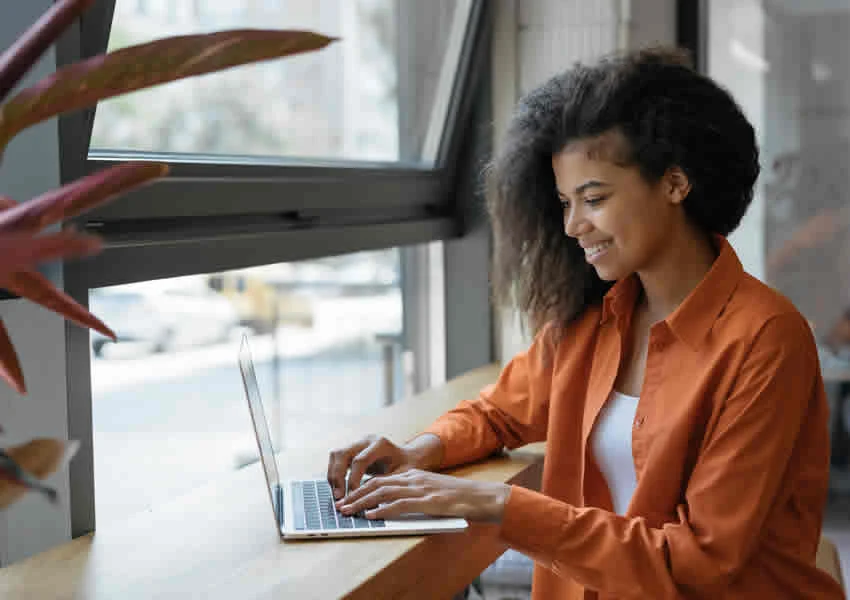 Imagem mostra uma mulher trabalhando em seu notebook em home office.