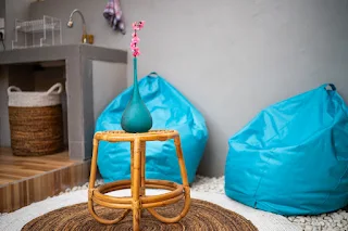 azure blue teardrop shaped beanbags next to a rattan table in a seating area