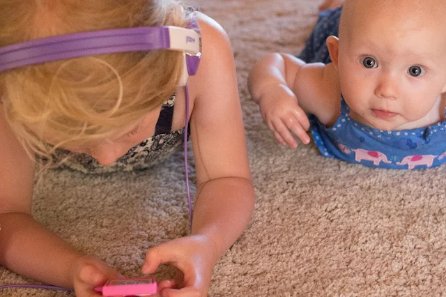 two children lying on a clean cream carpet one on an ipad the other dribbling which may void a warranty