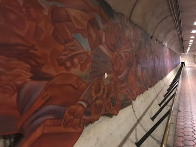 View down the Metro entrance tunnel showing a mural running the length of the wall.