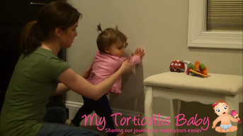 Baby with mild torticollis cruising along the wall with the support of mother.