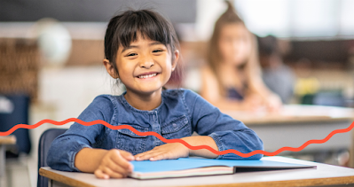 Child seated at school  desk with book opened photo for Autism Society