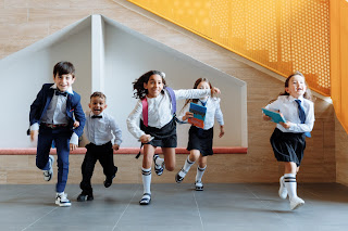 Children dressed in school uniform running back yo school