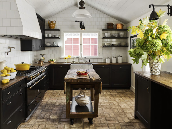 Azulejos de pared a la altura del techo en dimensiones alternas y pisos de ladrillo recuperado y encimeras de roble anclan la cocina en una hermosa rusticidad