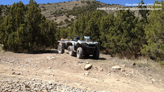 two ATV's parked on the side of a dusty trail