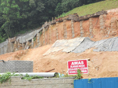 Will this hold?  During the press conference, workers quickly spread more covers against further erosion by the rain.