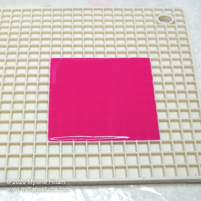 Bright pink resin poured in the shape of a square on a pixel trivet