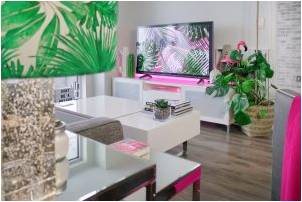 A turned on flat-screen led television in a living room with plants and attractive furniture.