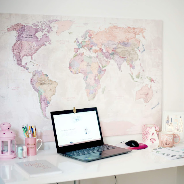 Laptop on desk in front of world map