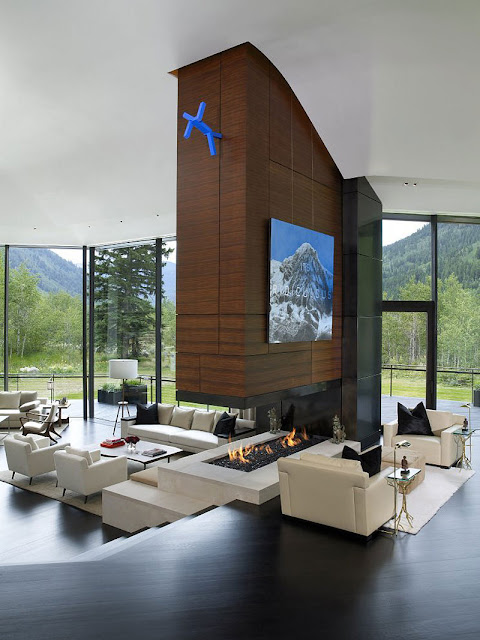 Living room of Aspen Residence by Stonefox with fireplace and big windows facing the forrest