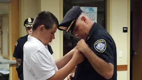 Deputy Chief Lynch's son adds the new pin to his father's uniform