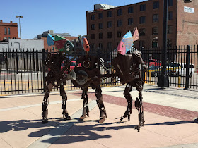 Photo of a sculpture of a band, 3 recycled metal characters with fish heads, playing saxophone, guitar, and accordion.