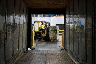 A man driving a forklift in a green warehousing and distribution organization