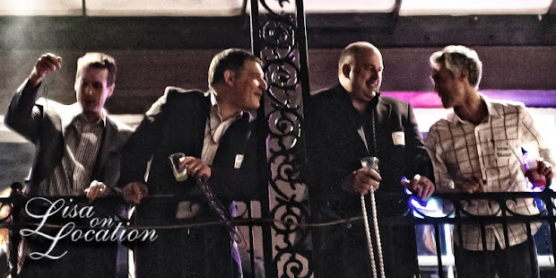 Men throwing beads from a second floor balcony on Bourbon Street in the French Quarter