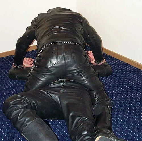 Two Men and four black leather on the ground wrestling faces unseen