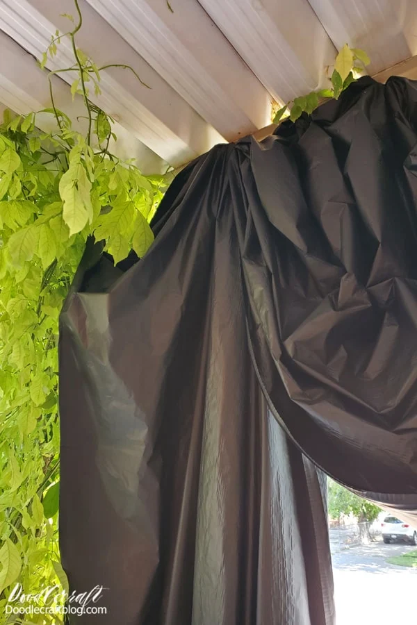 Begin by setting the backdrop for the spooky Halloween scene. I used a roll of plastic tablecloth to create a Victorian swag curtain on the front porch. This is key for hiding some surprises on the front porch. Plus, it adds to the spookiness.