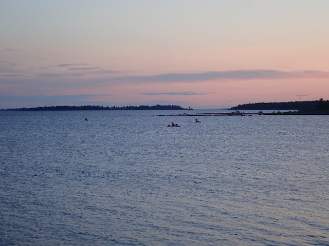 Kolme SUP-lautailijaa merellä auringonlaskun aikaan