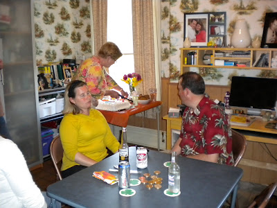 Gram lighting the candles on the cake with John and Stacy looking on