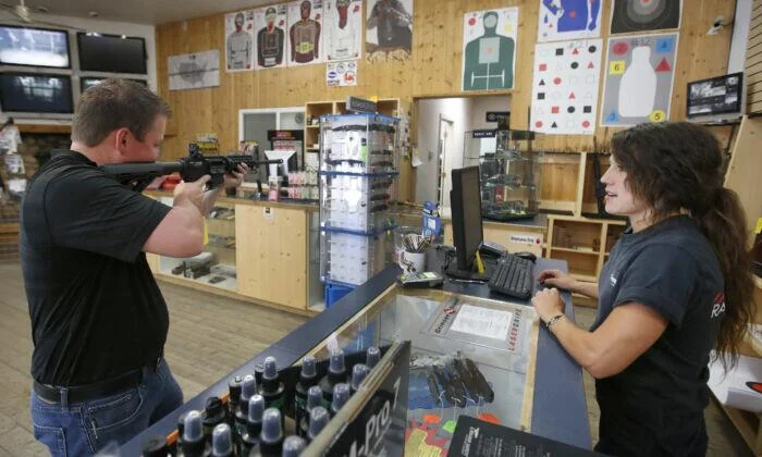 Sales clerk Courtney Manuring, shows an AR-15 semi-automatic gun to buyer at Action Target in Springville, Utah, on June 17.