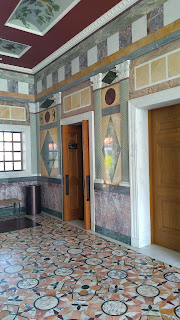 Room with multicoloured marble floor and walls and painted and coffered ceiling