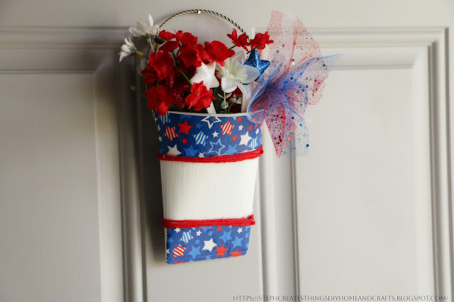 Painted metal hanging decoration with faux floral, twine and decorative napkin hanging from a door