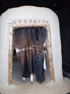 an animal skin covering drapes across a reproduction of a clay and wooden doorway in the style of pre-19th century Omaha area Native Americans