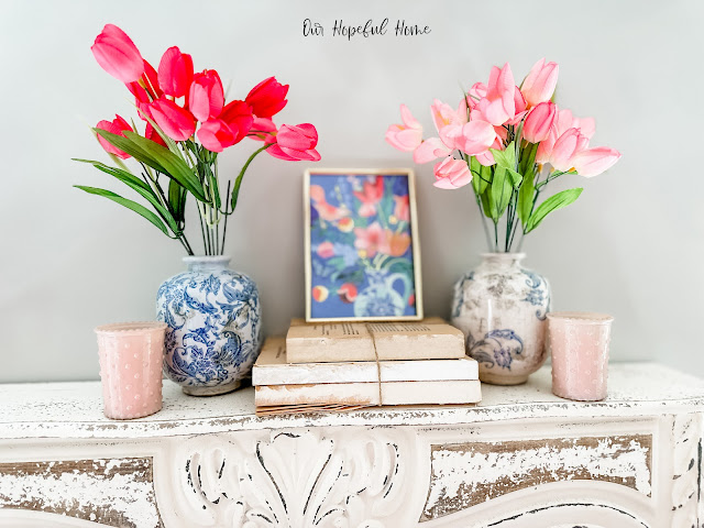 floral print in gold frame on mantel with tulips and books