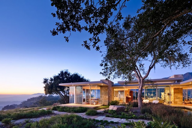 View of the Home Exterior with Stone Wall and the Wide Glass Walls