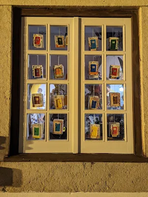 Window with small ceramic doors hanging on each pane. The picture was taken at night in Obidos Portugal