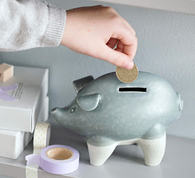 ceramic piggy bank with coin being inserted