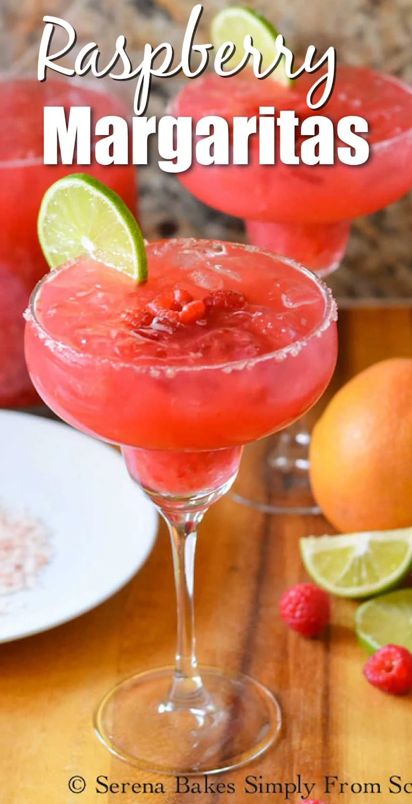 A side shot of 2 Raspberry Margaritas on a wooden cutting board with white text at the top Raspberry Margaritas.