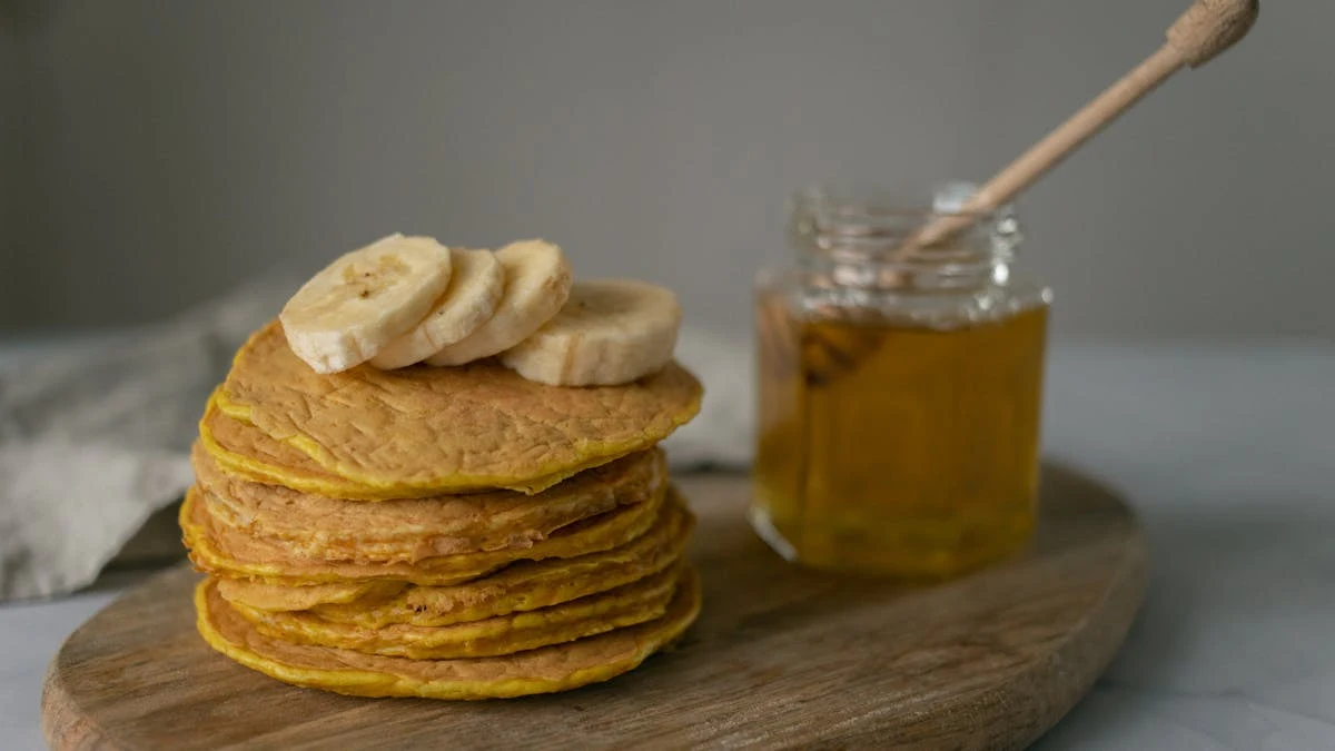 Pancakes with Bananas near Honey on Chopping Board