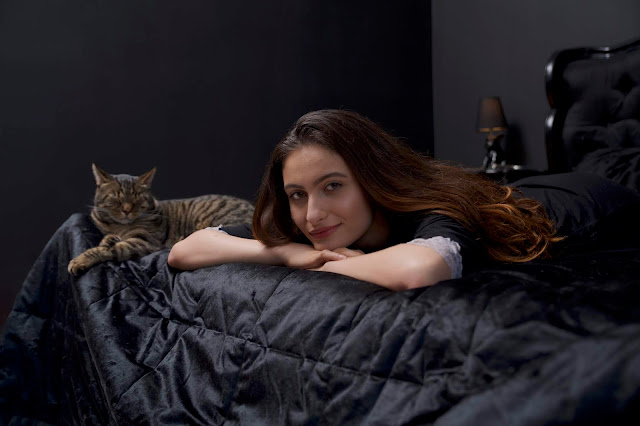 model on a bed with a cat