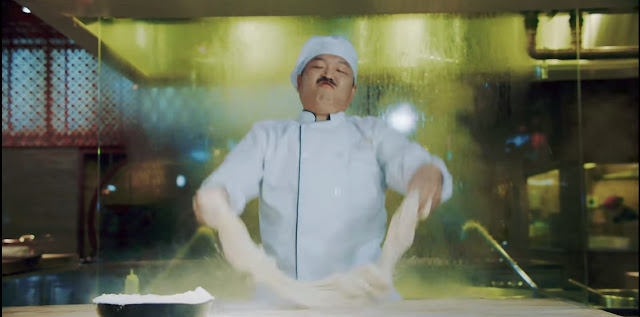 Psy con bigote vestido de chef, amasando una masa (no hay mucha mas información) en un modo muy loco