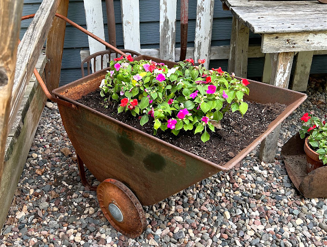 Photo of a rusty vintage garden cart planted with impatiens.
